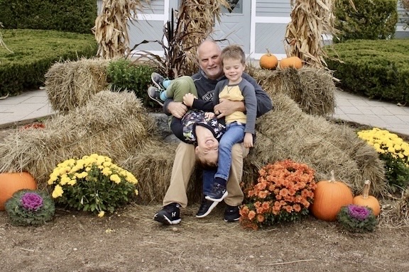 Small boys and Grandfather sitting on hay and laughing
